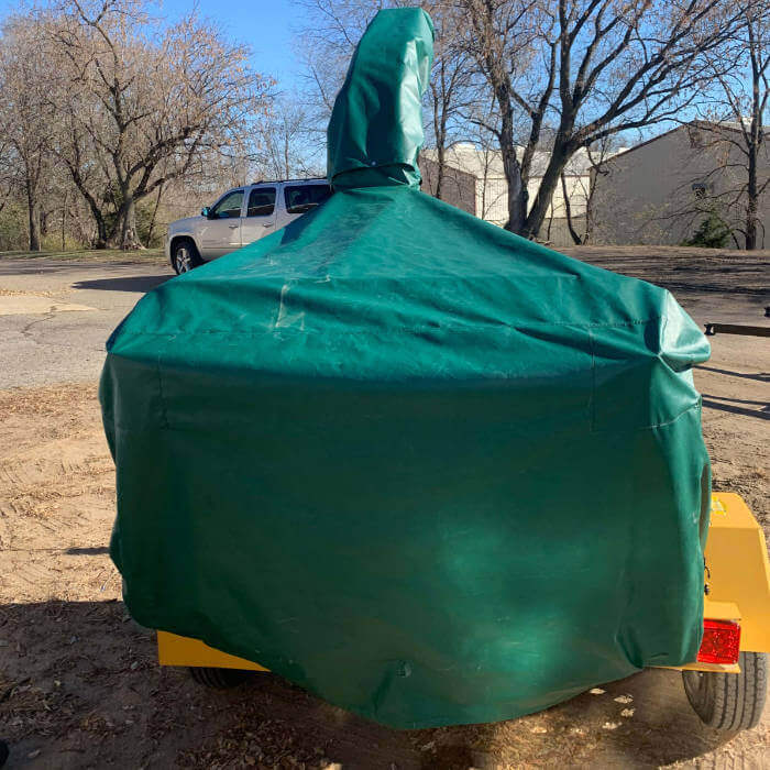 The back of an orange woodchipper with a green cover